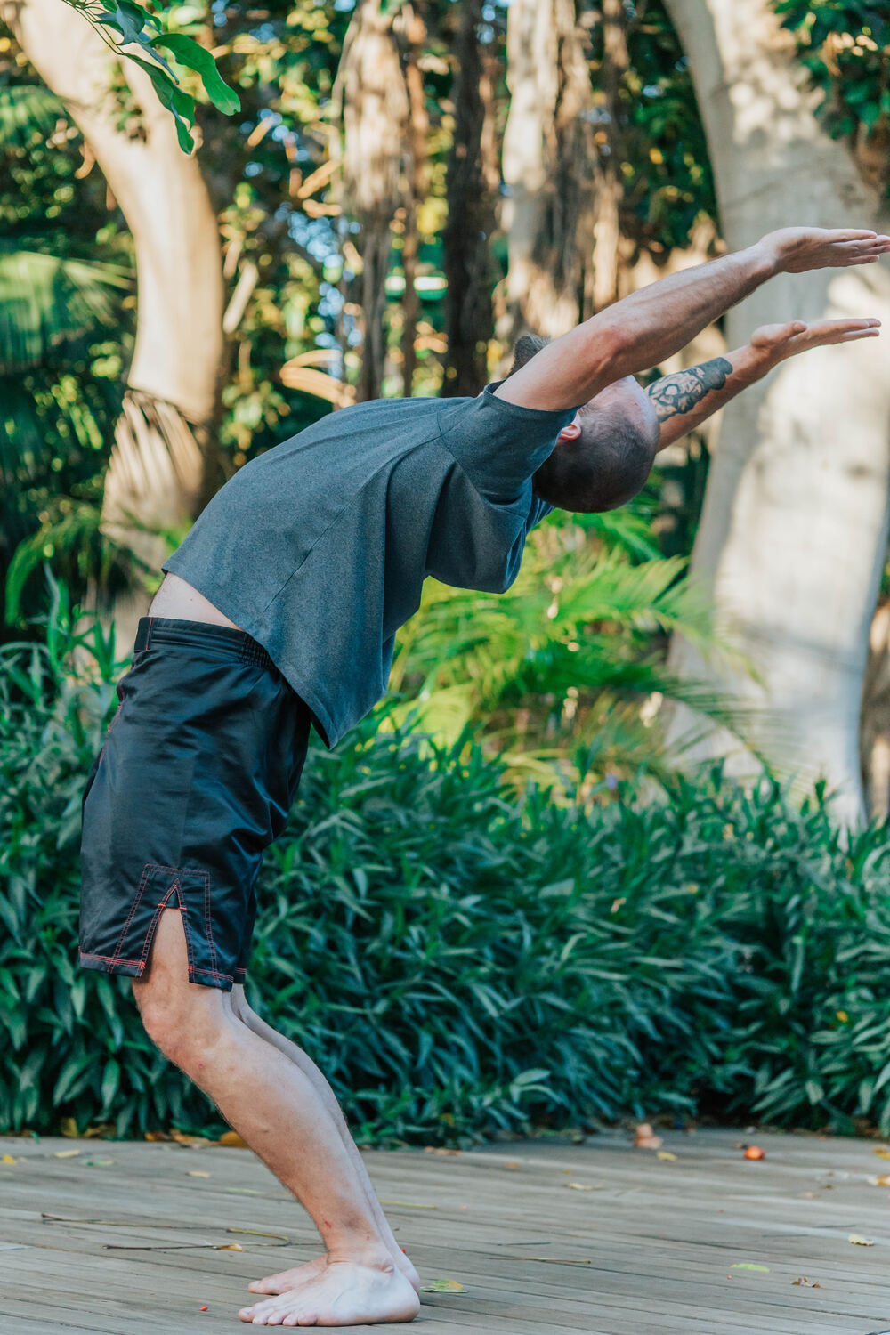 Joe in a deep standing backbend, arms overhead, in morning light