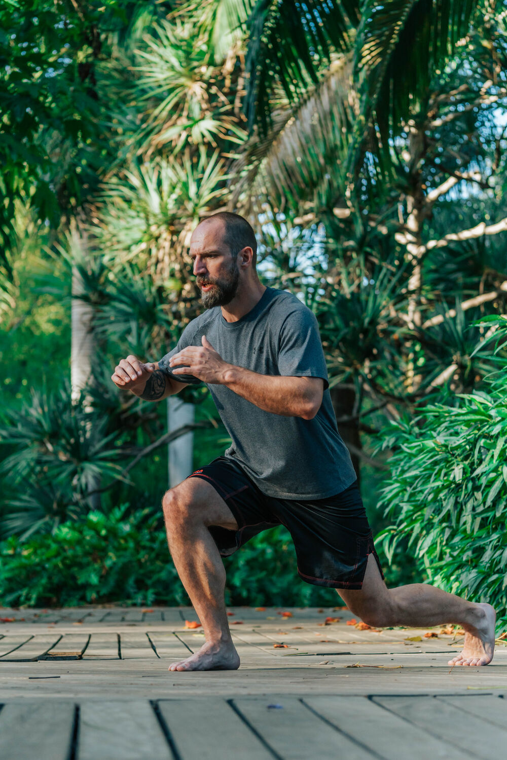 Joe holding a deep lunge with fists raised, training outdoors